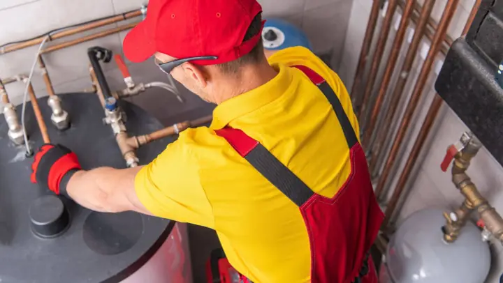 Plumber repairing the piping on top of a water heater